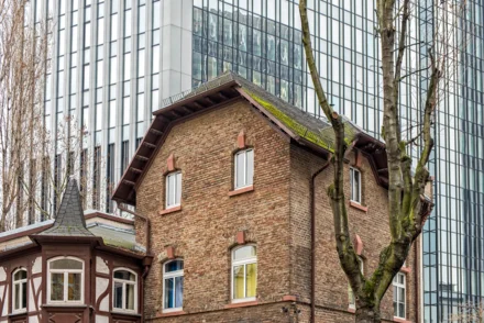 Historisches Backsteingebäude mit Fachwerkerker vor spiegelnder Glasfassade eines Hochhauses